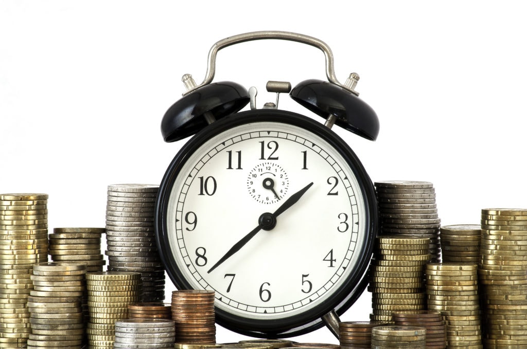 Alarm clock standing with coins on metal plate